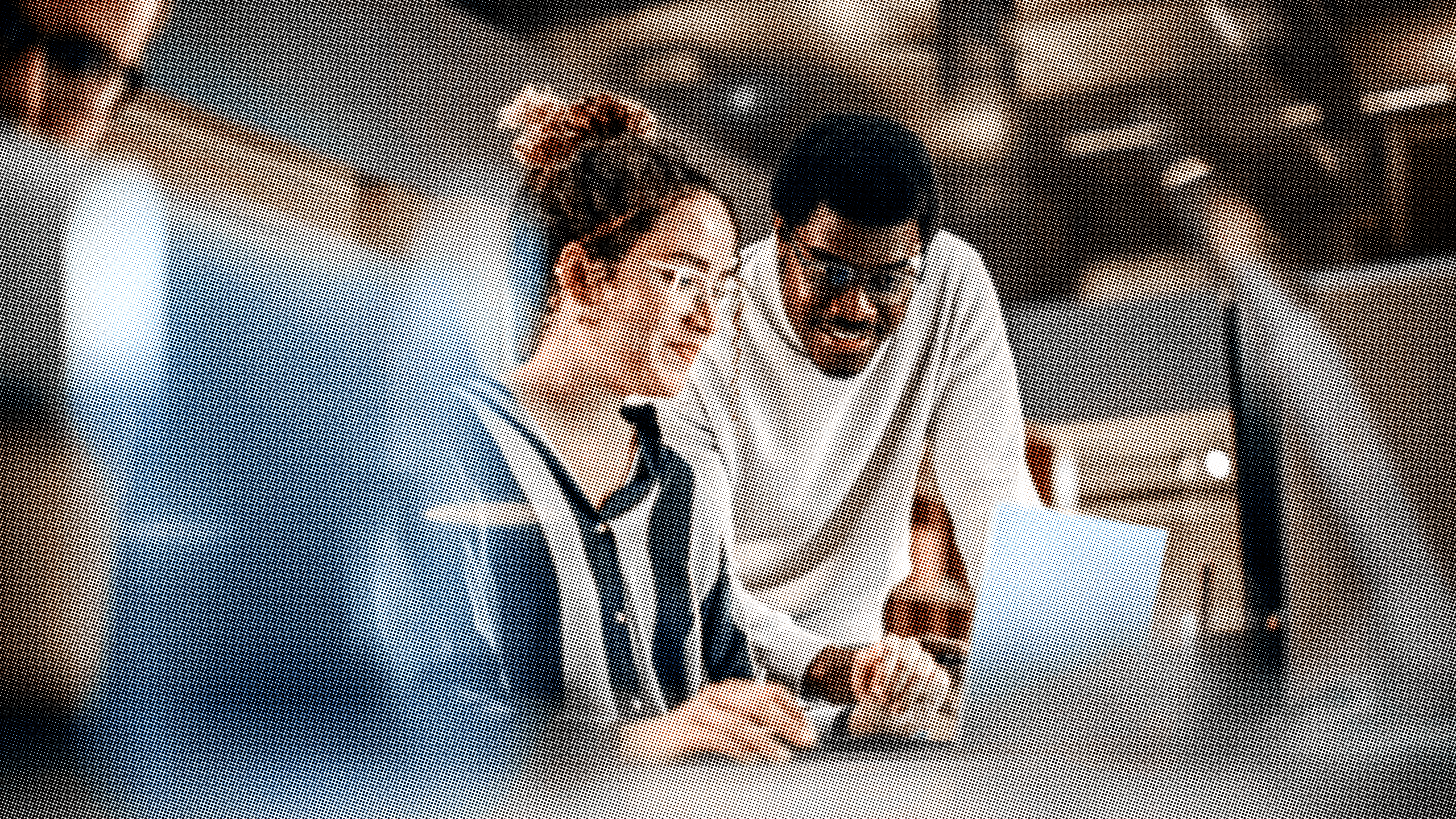 Two people smiling while working off a laptop